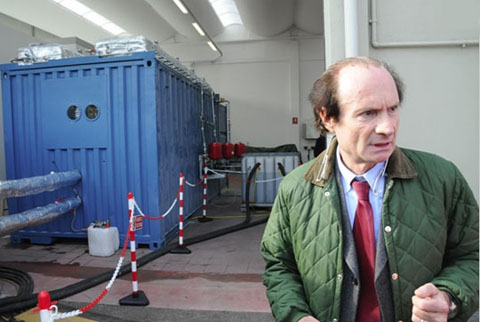 .Andrea Rossi met achter hem, in de blauwe container, de eerste 'E-cat'-proefgenerator voor industrieel gebruik.