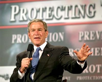 George Bush in zijn rol als beschermende president; achter hem de leus 'Protecting the Homeland'.. Ondertussen zijn de Amerikanen veel van hun fundamentele burgerrechten kwijt; zélf ingeleverd..! Een prachtig motief voor de valse-vlag-aanslagen van 9/11 komt hiermee haarfijn in beeld! De macht uit handen nemen van burgers, die in 'ruil voor bescherming' hun kracht en macht uit handen geven aan JUIST de boeven..